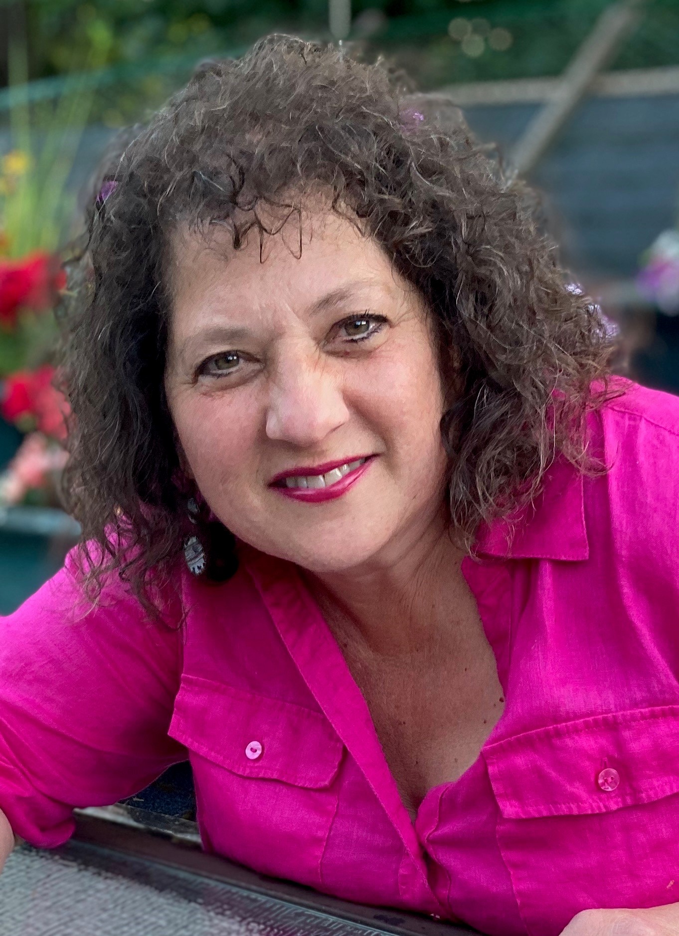 Woman with dark hair and pink shirt smiling