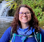Woman with glasses standing in front of waterfall