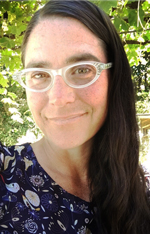Woman with long dark hair and white glasses smiling