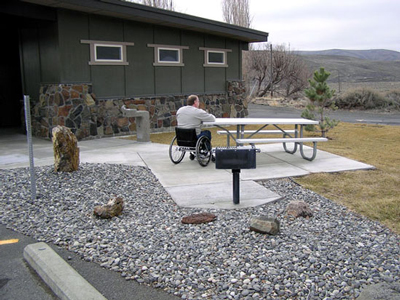 Man in wheelchair at picnic table and grill