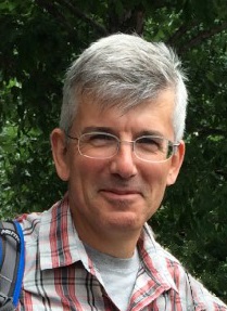 Man with gray hair and glasses smiling