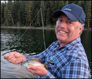 Man in blue checkered shirt wearing a blue hat and holding a fish