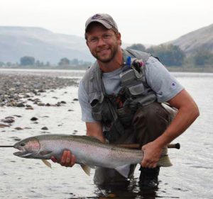 Man standing in river holding fish