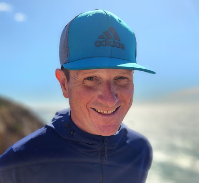 Man smiling while wearing a blue hat and blue jacket