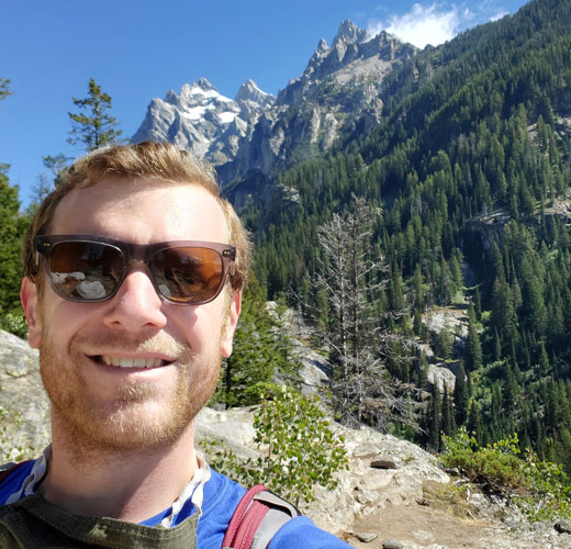 Picture of man wearing sunglasses in front of mountains