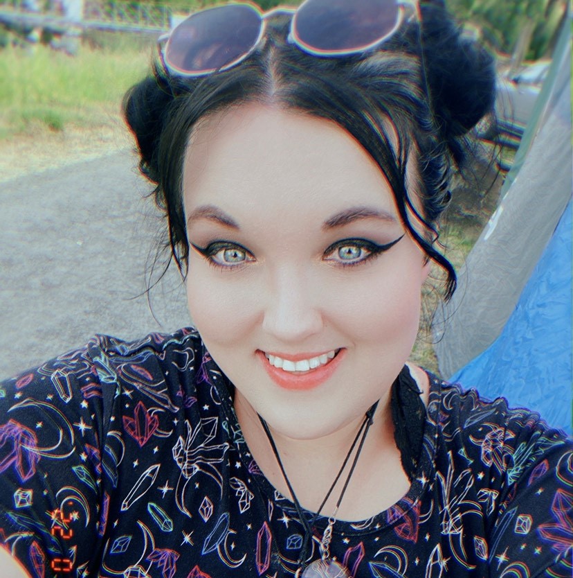 Dark haired woman with sunglasses atop her head taking a selfie.