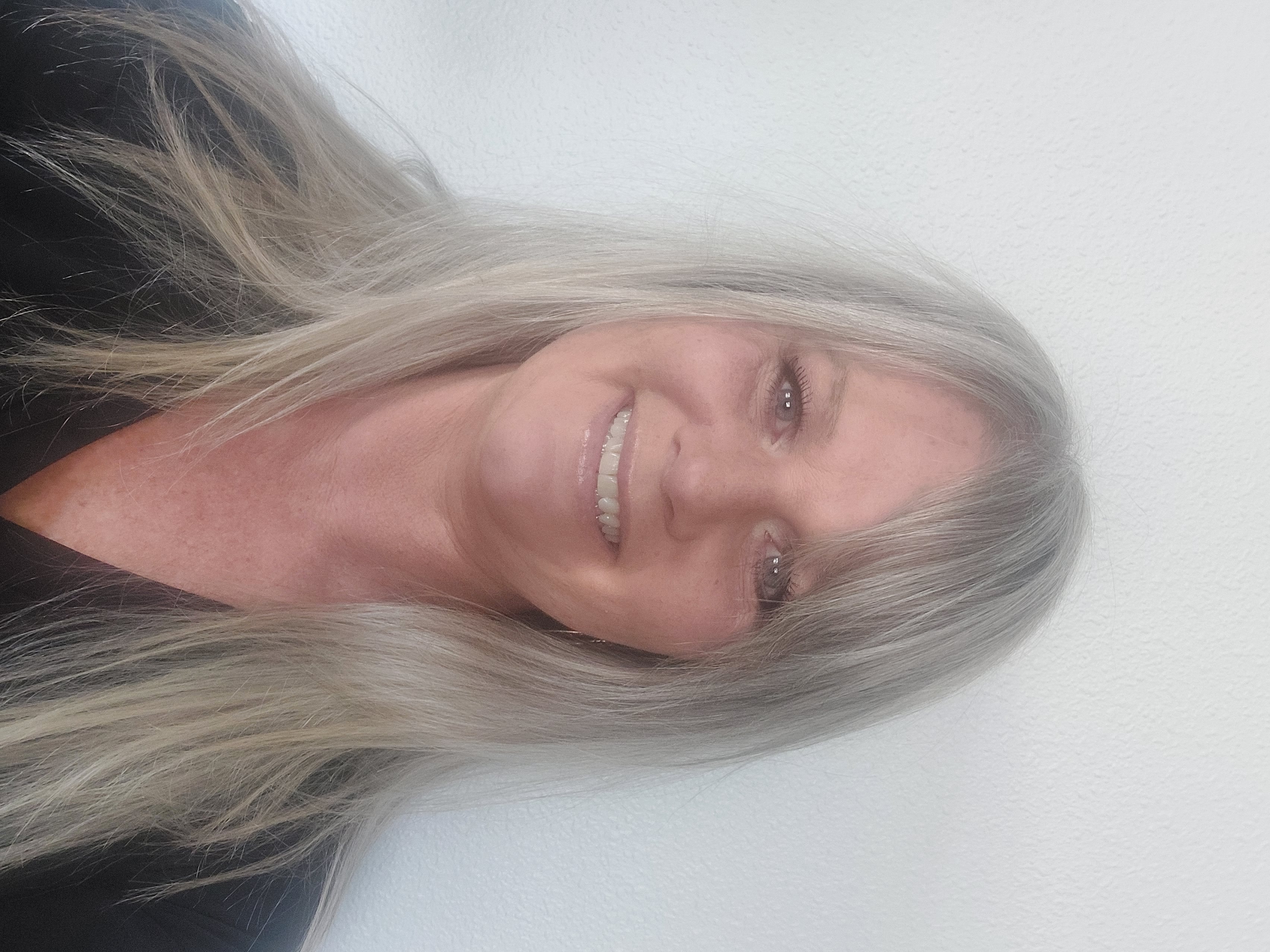 A woman with long gray hair smiling at camera