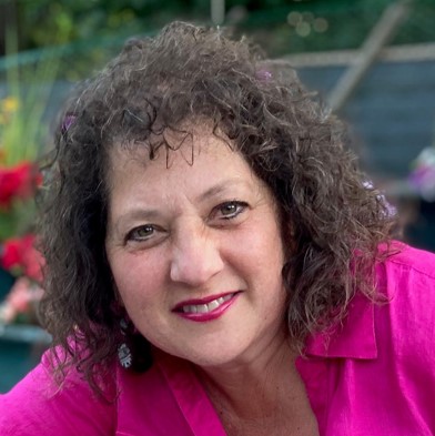 Woman with dark hair and pink shirt smiling